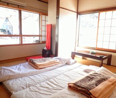 Sunlit tatami room with futon bedding, low table and shoji screens at Oyado Matsubaya in Gunma