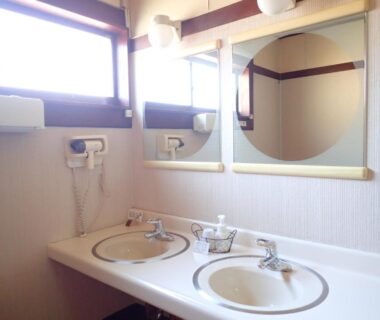 Two ceramic sinks with round mirrors, wall-mounted hairdryer and soap dish in a ryokan washroom at Oyado Matsubaya, Gunma
