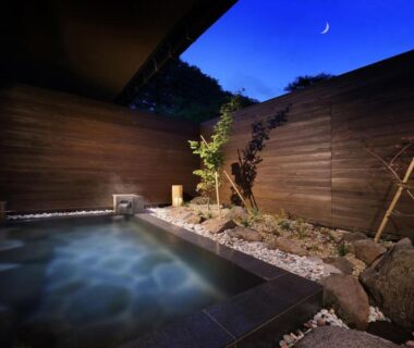 Stone-lined open-air onsen with wooden fence at Oyado Morinone in Yamagata