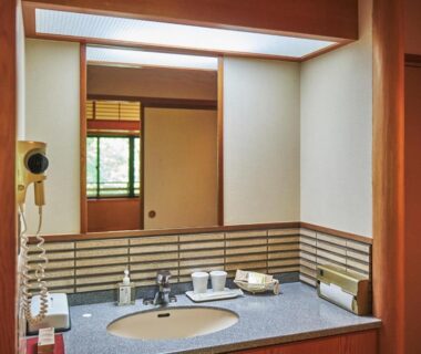 Traditional ryokan washbasin and mirror with wood accents and shoji window at Oyado Nagomino Nagano