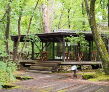 Wooden terrace pavilion with table seating amid green forest at Oyado Nagomino, Nagano, Chūbu, Japan
