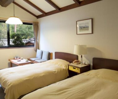 Twin beds with low table and garden view at Oyado Nagomino Nagano