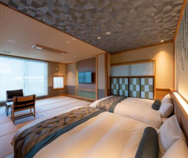 Spacious tatami-floored twin room with low table, chairs, shoji screens and soft lighting at Oyado Sansui Nagano