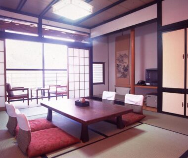 Traditional tatami room with low table, zabuton cushions, shoji screens and tokonoma at Oyado Sansui in Nagano