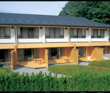 Two story ryokan with wooden verandas, sliding doors and trimmed hedges at Oyado Sansui, Nagano