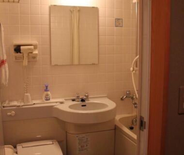 Small tiled bathroom with sink, toilet, mirror and compact bathtub at Oyado Seri in Hyōgo, Kansai