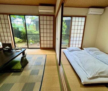 Tatami room with low table, futon, shoji screens and sliding doors to a garden at Oyado Tamayura Oita