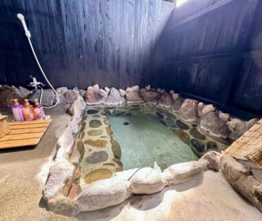 Indoor stone-lined onsen with wooden shower bench at Oyado Tamayura 18 years or older, Ōita, Kyūshū, Japan