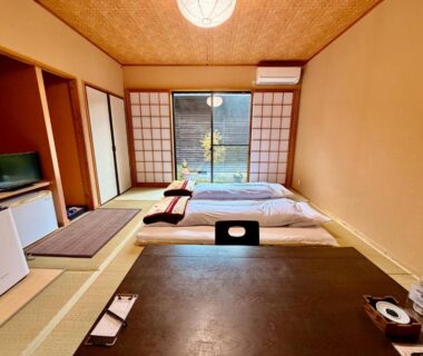 Traditional tatami room with futon beds, low table, shoji screens and garden view at Oyado Tamayura, Ōita