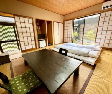 Traditional tatami room with futons, low wooden table, shoji screens and small garden view at Oyado Tamayura in Oita