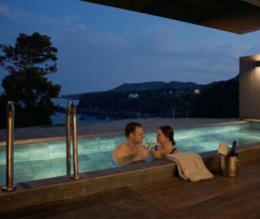 Couple in outdoor onsen at Oyado The Earth overlooking Mie coastline at dusk