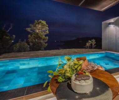 Illuminated outdoor soaking pool with dessert on wooden table at Oyado The Earth, Mie, Japan
