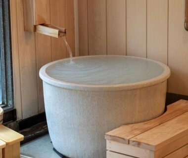 Round soaking tub with water spout in indoor bath area at Oyado Tsuruya Nagano