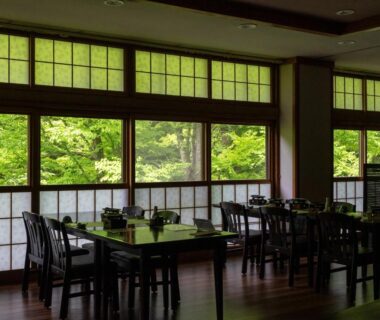 Dining area with wooden tables, shoji screens and green garden views at Oyado Tsuruya in Nagano