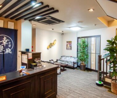 Reception area with wooden desk, blue noren, seating sofas and indoor plants at Oyado Yukizumi in Gunma