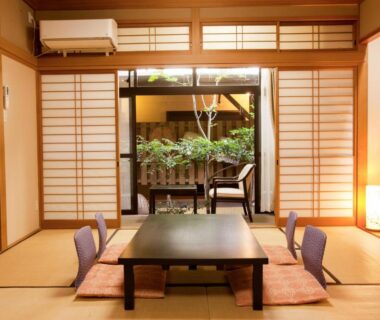 Tatami room with low table, floor chairs, shoji screens and small garden at Oyado Yumechidori Saga