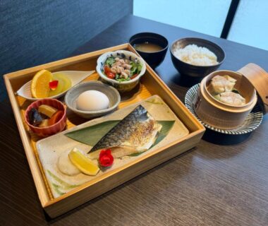 Grilled fish breakfast set with rice, miso soup, pickles and bamboo steamer on wooden tray at ryokan