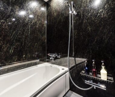 Dark marble in-room bath with tub, handheld shower and toiletries at PROSTYLE Ryokan Yokohama Bashamichi, Kanagawa, Japan