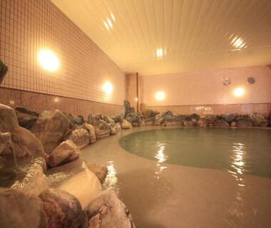 Indoor rock-edged onsen bath with tiled walls at Park Hotel Miyabitei in Hokkaidō