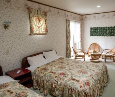 Floral bedroom with two beds, rattan chairs and small table at Pension Balmy in Tochigi, Japan