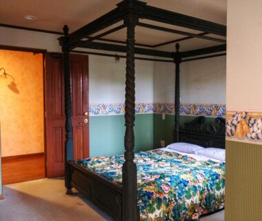 Wooden four-poster bed with floral quilt in a guestroom at Pension Balmy, Tochigi