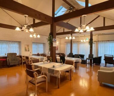 Bright communal lounge with exposed wooden beams and mixed seating at Pension Balmy, Tochigi, Kantō Japan