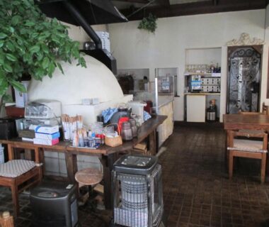 Wooden dining area with heaters, tables and plants at Pension Hakuba 70 in Nagano Chūbu