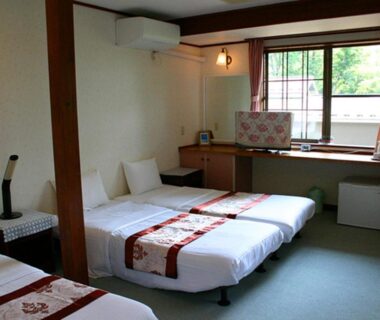 Twin beds with decorative runners, desk and window in Pension Marie guest room, Yamanashi, Chūbu