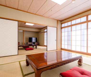 Traditional tatami room with low wooden table, red floor cushions and shoji at PiDDs Family 熱海, Shizuoka