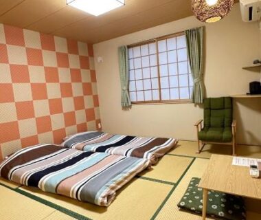 Tatami room with futons, low table, shoji window and patterned wall at Plum House Otaru, Hokkaido