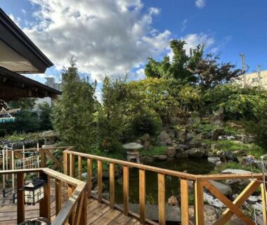 Wooden deck overlooking a pond and lush garden at Plum House Otaru, Hokkaidō