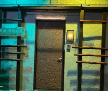 Nightlit entrance with colored lights, stepping stones and wooden rail beside door at Private Inn Bambee, Hyōgo