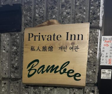 Wooden entrance sign reading Private Inn Bambee with Japanese and Korean characters on a textured stone wall