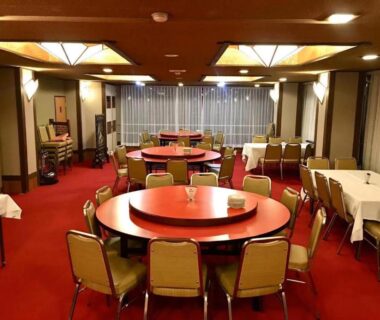 Communal round tables with green chairs and red carpet in Rakki OnsenRyokan dining hall, Nagano