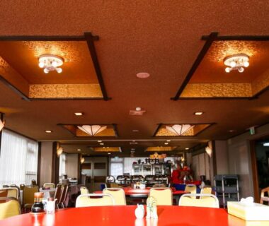 Spacious dining room with red tables and chandeliers at Rakki OnsenRyokan in Nagano, Chūbu region