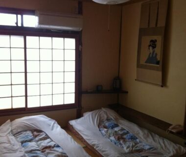 Traditional tatami room with two futons, shoji screens and tokonoma with hanging scroll at Rakucho Ryokan Kyoto