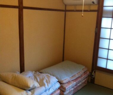 Stacked futon bedding on tatami with shoji screen at Rakucho Ryokan in Kyoto Kansai
