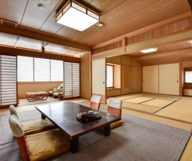 Spacious tatami room with low table, floor chairs and shoji screens at Rakusuien in Yamanashi