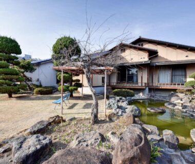 Traditional ryokan exterior with pond, rock garden and trimmed trees at Rakusuien in Yamanashi