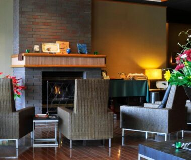 Lounge seating with fireplace, piano, floral arrangement and wooden floors at Rakuyu in Yamanashi