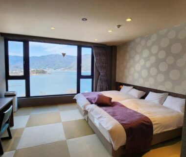 Tatami-floored room with twin low beds and large window overlooking a lake and distant mountains