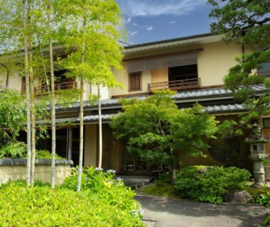 Two-story ryokan building with manicured garden, bamboo and stone path at Rangetsu in Kyoto