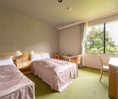 Twin room with two single beds, green carpet, desk and window with trees at Rantei, Miyagi