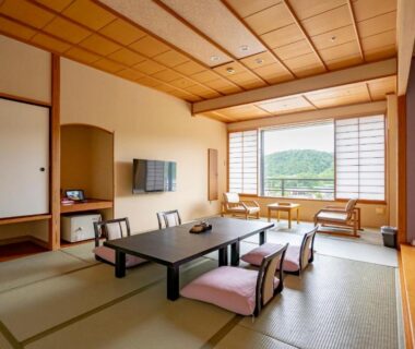 Spacious tatami room with low table, floor cushions, shoji screens and view of greenery at Rantei, Miyagi