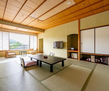 Traditional tatami room with low table, floor cushions, shoji screens and large window overlooking greenery at Rantei, Miyagi