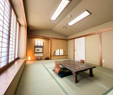 Traditional tatami room with low table, cushions, shoji screens and tokonoma alcove at Matsumoto ryokan in Iwate