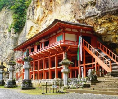Red wooden cliffside temple with stone lanterns near Japanese inn Matsumoto, Iwate Tōhoku