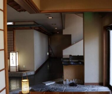 Traditional entrance corridor with tatami, shoji doors, wooden stairs and warm lantern lighting at Renovated room Japanese inn Matsumoto Iwate