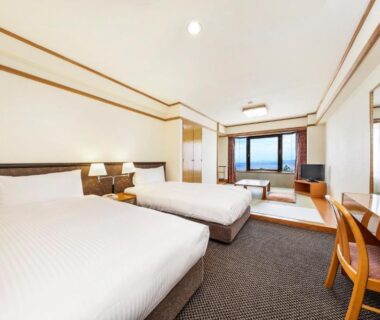 Twin beds with tatami seating and balcony window at Resorpia Beppu, Ōita