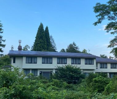 Two-story building nestled in lush greenery at Resort Project Myoko Kogen Hot Spring in Niigata
